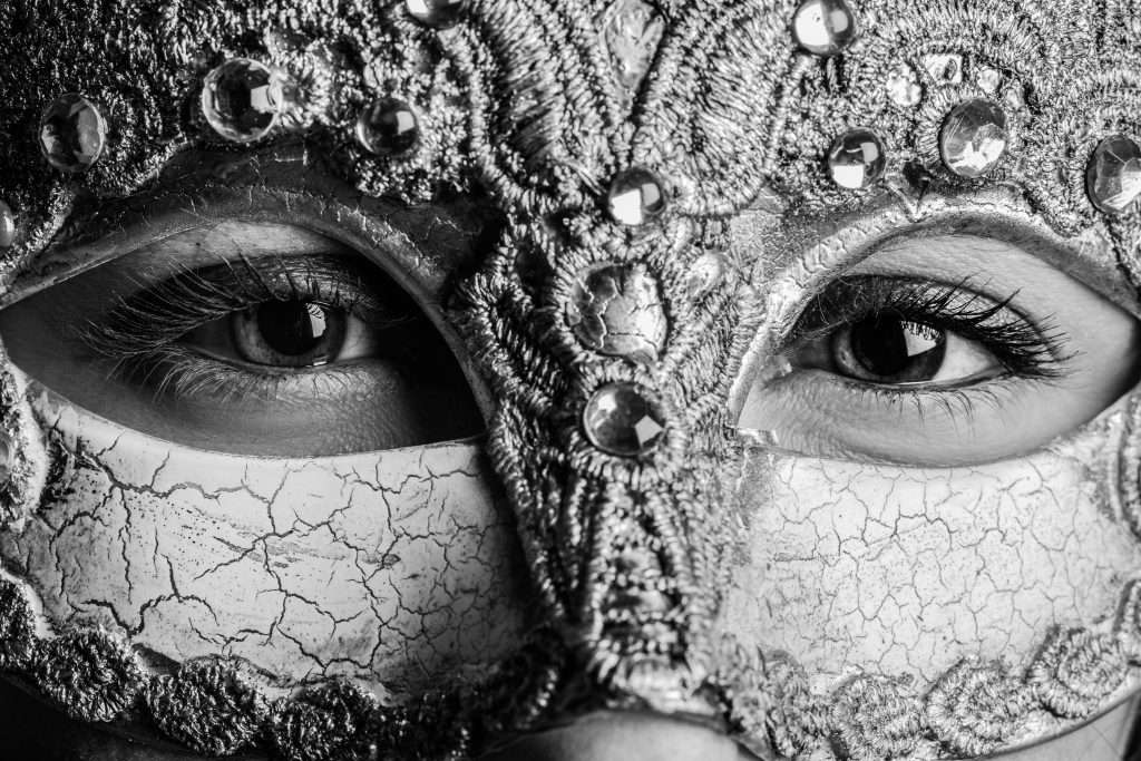 woman with sad eyes hiding behind a gorgeous beaded lace mask